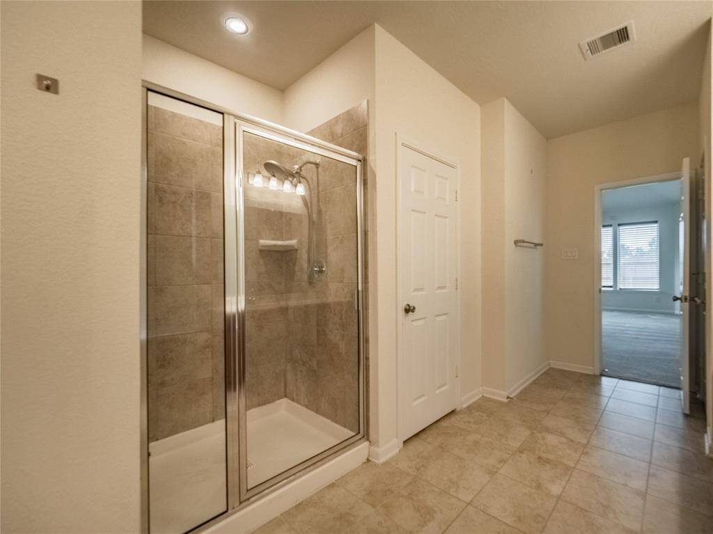 primary walk in shower with glass doors