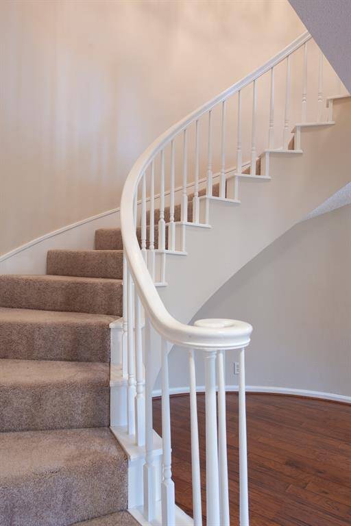 This spiral staircase is a captivating feature, transforming the entryway into an elegant and dynamic space. The design combines both form and function, with the staircase itself becoming a striking architectural element.