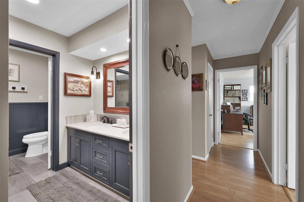 Full guest bathroom featuring a modern vanity with a dark cabinet and stylish lighting and a separate toilet area for added privacy