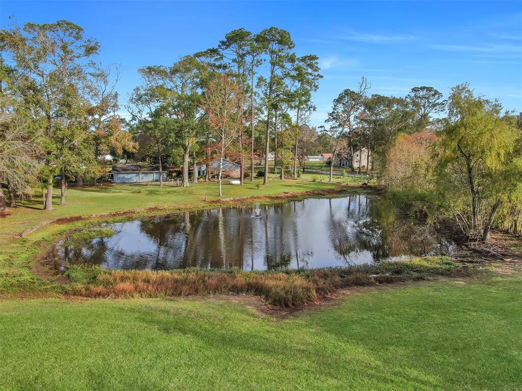 This serene property features a picturesque pond surrounded by lush greenery and mature trees, offering a peaceful, natural setting perfect for relaxation and outdoor enjoyment