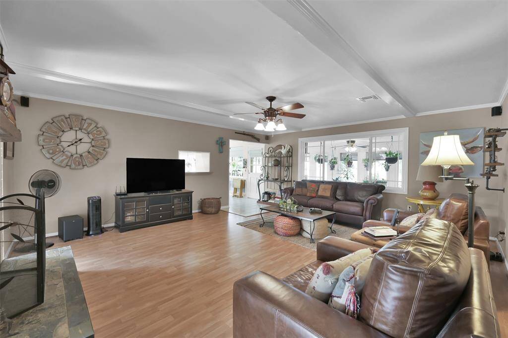 Spacious living room with cozy feel features ample natural light from the sunroom perfect for relaxation and entertaining