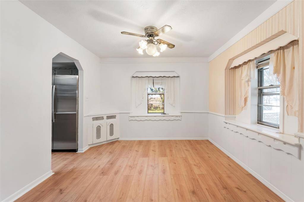 Cute dining room with a ceiling fan, decorative windows and some built-in storage.