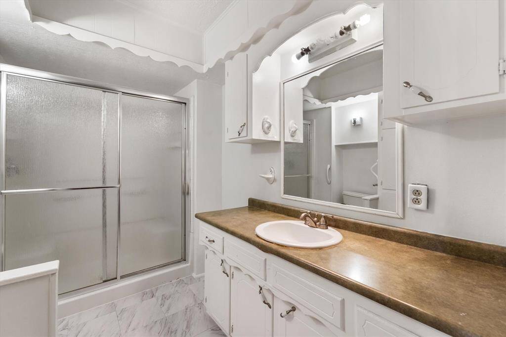 Full bathroom downstairs offers tons of storage, and a walk in shower with a sliding door.