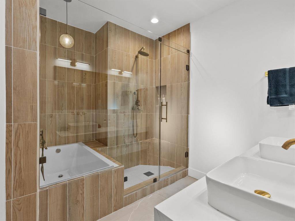 Elevate your daily routine in this luxurious bathroom featuring elegant finishes, a spacious glass shower, and modern dual sinks.