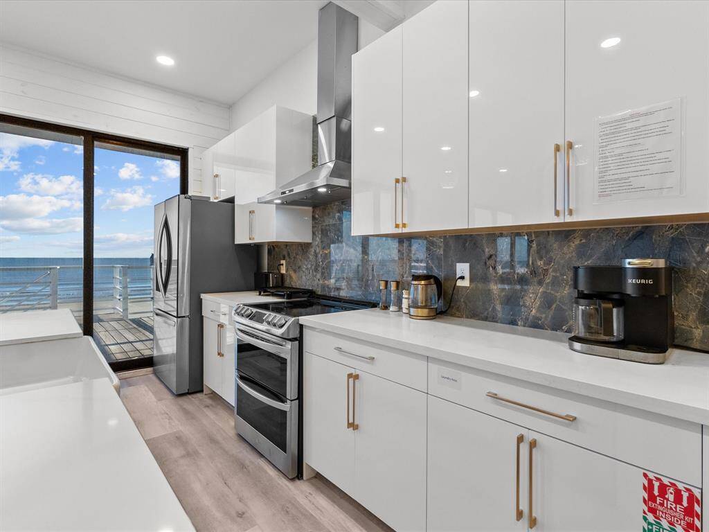 Sleek, modern kitchen with stunning ocean views, featuring high-gloss cabinets, stainless steel appliances, and elegant marble backsplash. Perfect for culinary enthusiasts.