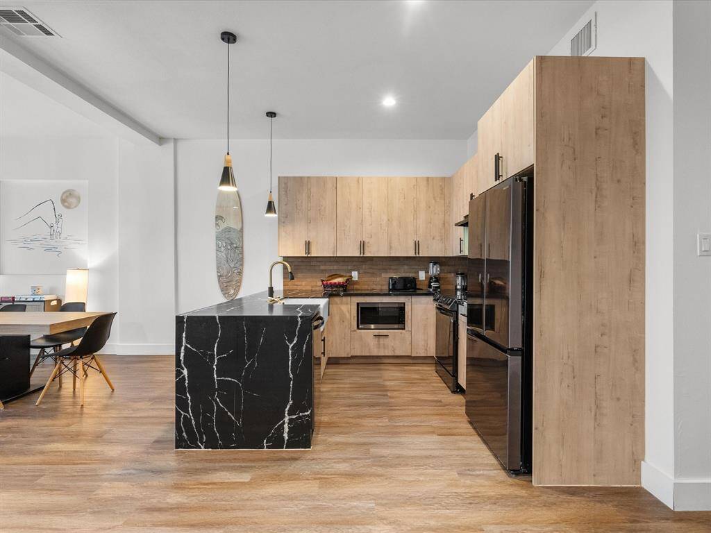 Sleek and modern kitchen featuring elegant black marble countertops, warm wood cabinetry, and stylish pendant lighting. Perfect for culinary enthusiasts and entertaining.