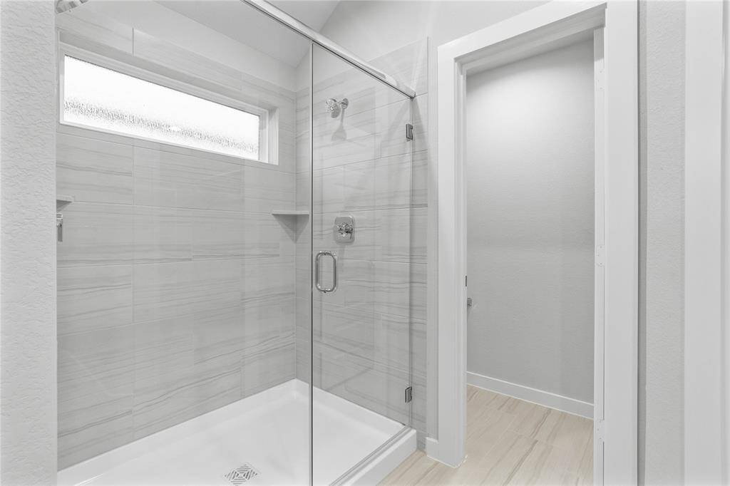 This additional view of the primary bath showcases an oversized walk-in shower with tile surround.