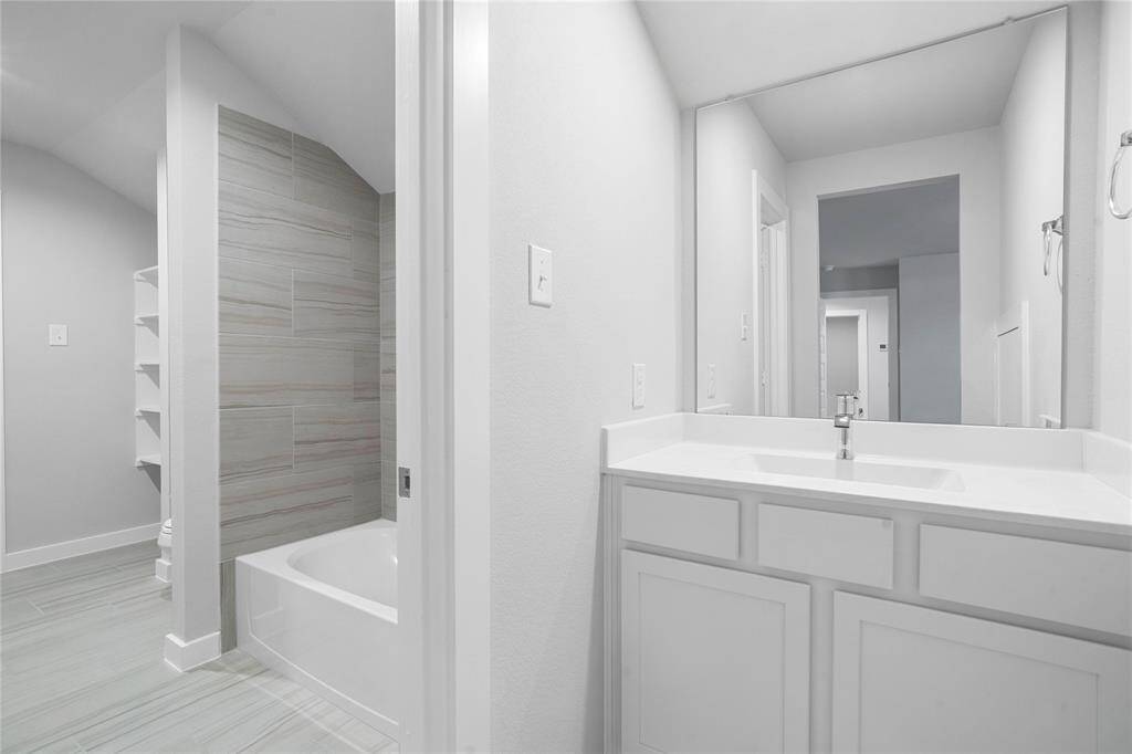 Secondary bedroom features plush carpet, custom paint, high ceilings with ceiling fan, and a large window with privacy blinds. This secondary bedroom shares a jack-n-jill bathroom and access to its private vanity sink.