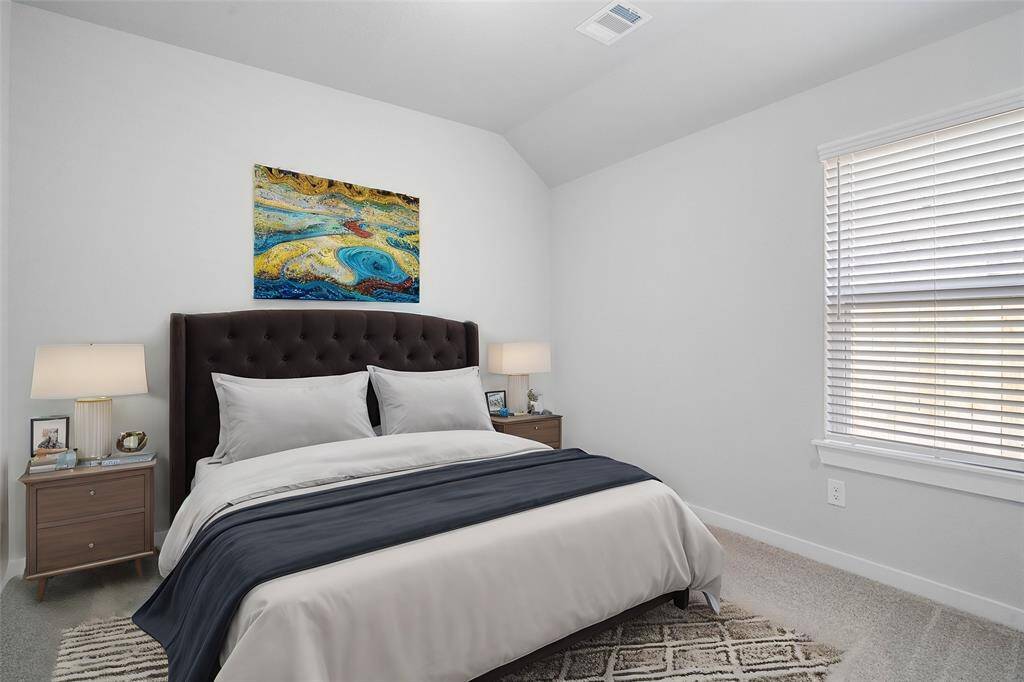 Secondary bedroom features plush carpet, custom neutral paint, ceiling fan with lighting and a large window with privacy blinds.