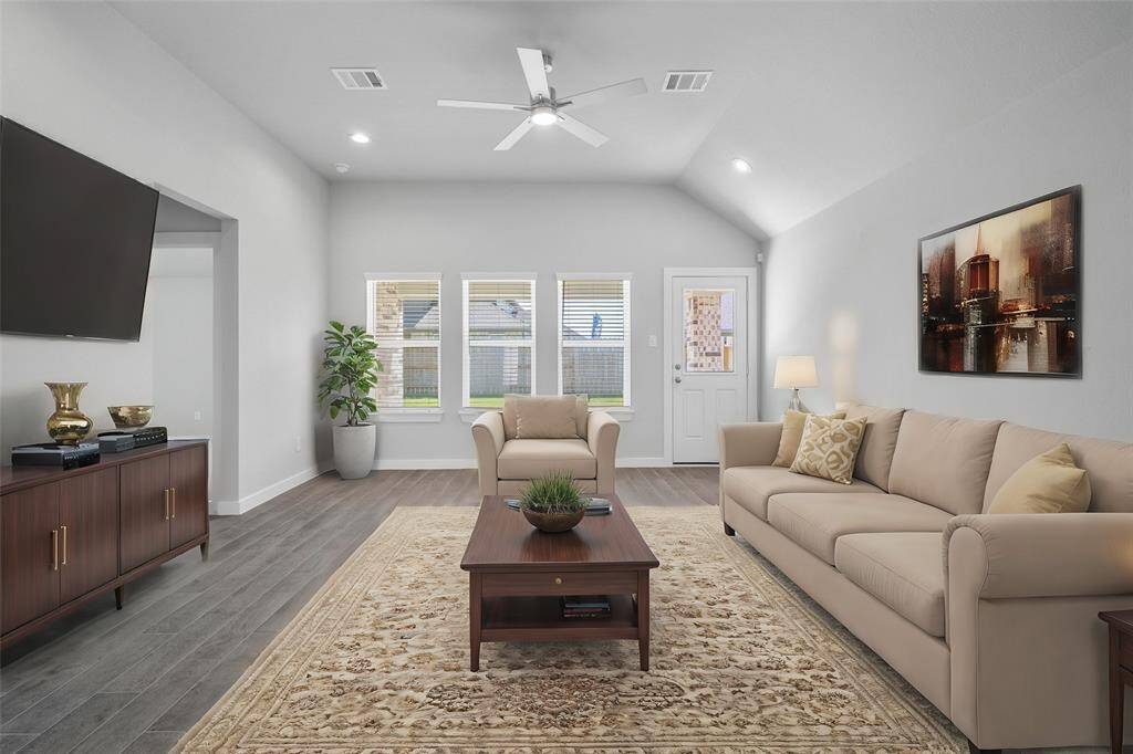 Secondary bedroom features plush carpet, custom neutral paint, ceiling fan with lighting and a large window with privacy blinds.