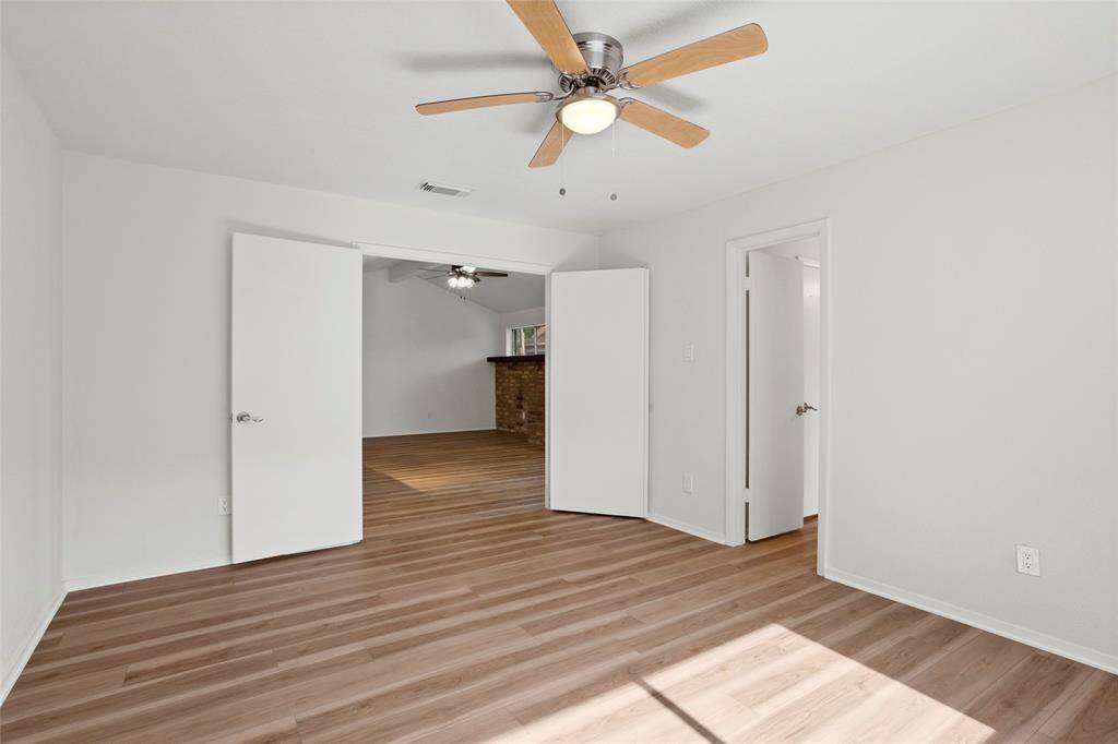 Another view of the primary bedroom with the double doors, looking into the living room. Door on the right is the primary bathroom.