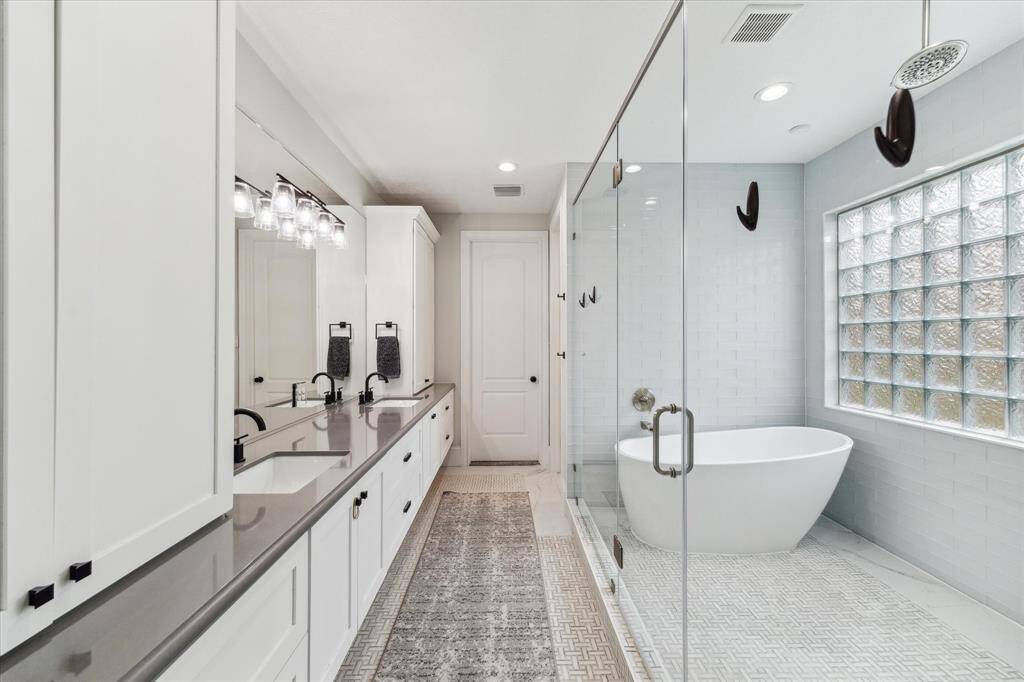 Porcelain tub, double sinks, and walk in shower with finishes in marble tile