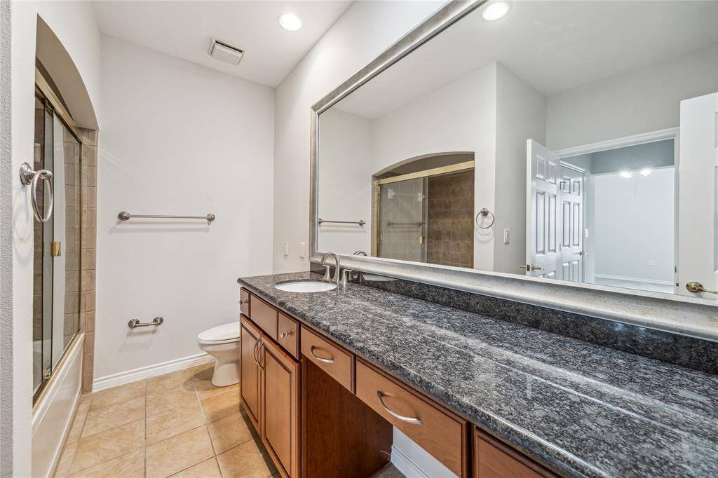 Primary ensuite bathroom with a soaking tub, vanity, granite counter tops, and linen closet.