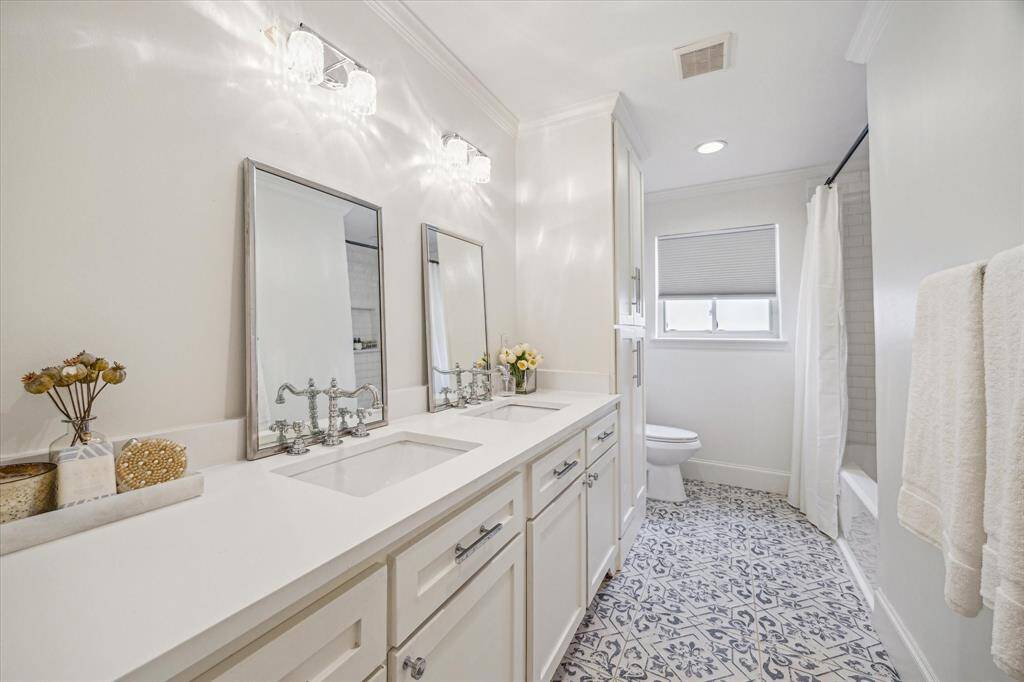 Hall bath with tub shower and counter with dual sinks. Whimsical l floor.