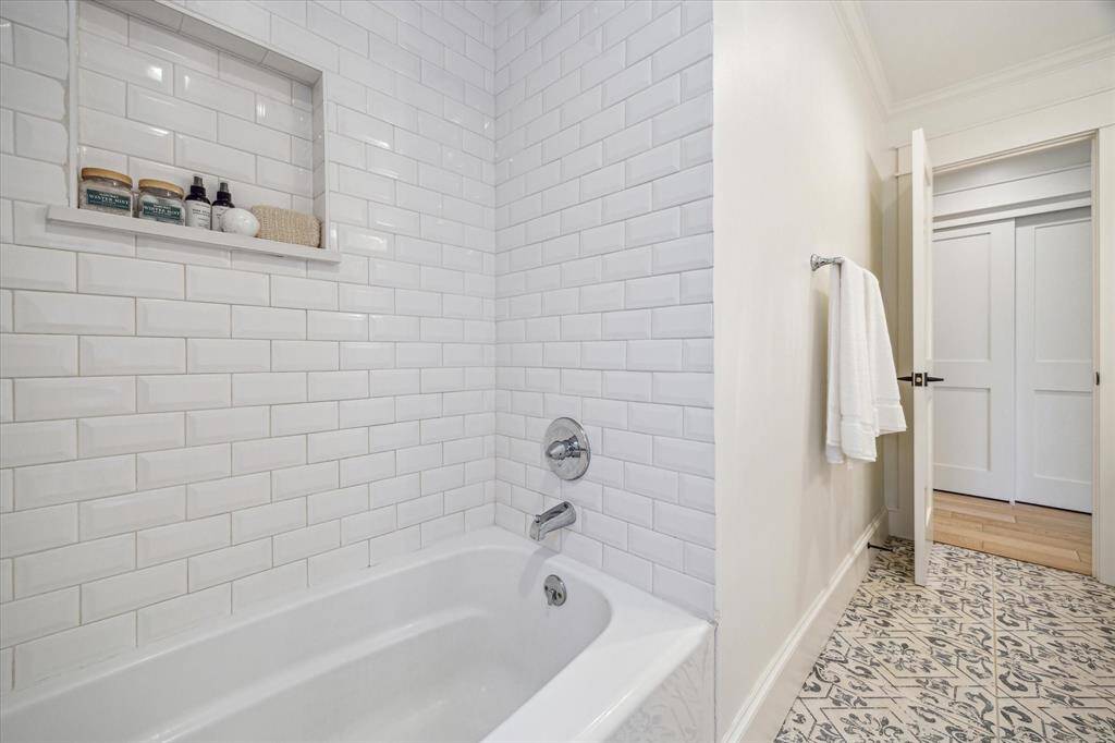 Tub in hall bath has recessed area for bath accessories.