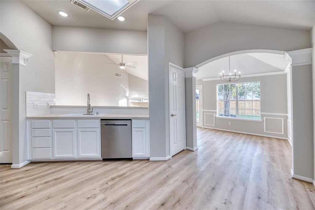 Open-concept kitchen and dining area with modern finishes! The dining area is enhanced by a large window and a stylish chandelier, offering a view of the backyard.