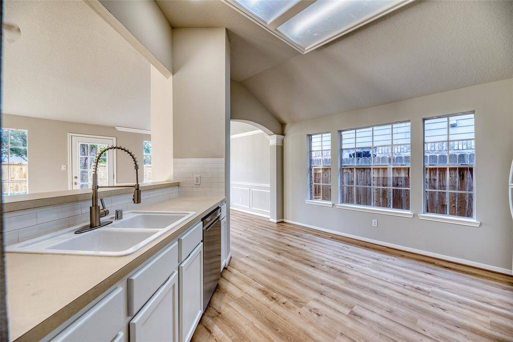 Bright, open-concept kitchen and dining area featuring a modern sink with a sleek faucet, white cabinetry, and stainless steel appliances.