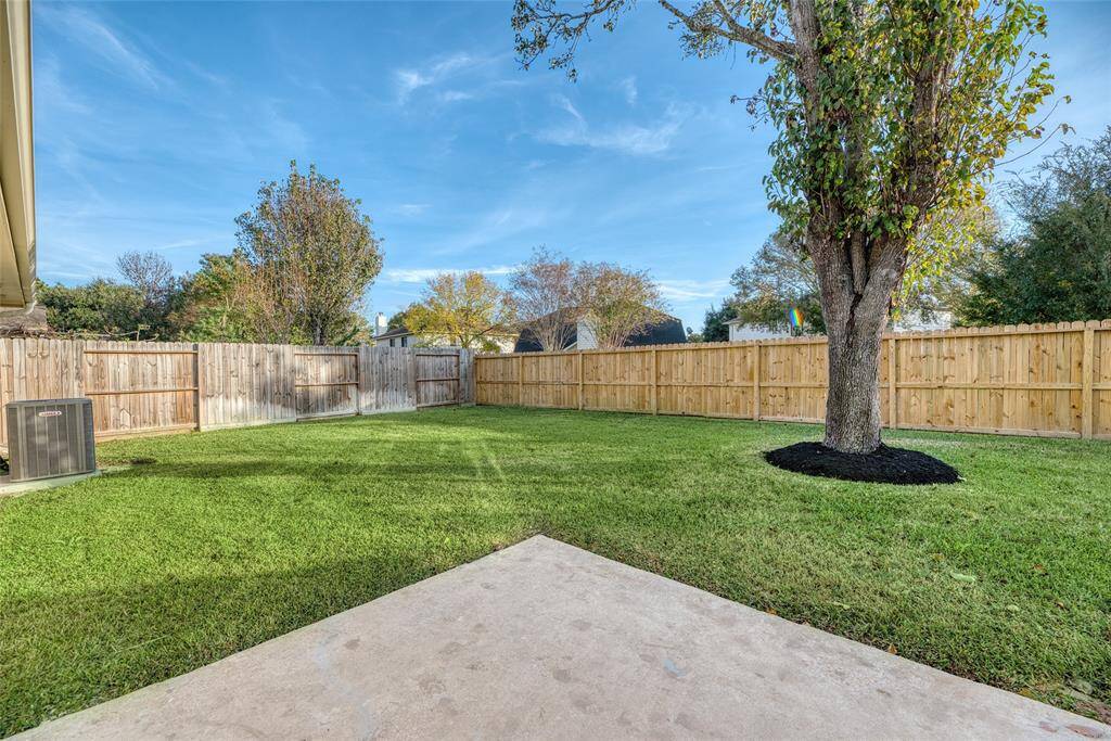 Fenced backyard with a large tree and well-maintained lawn, perfect for outdoor activities and privacy.