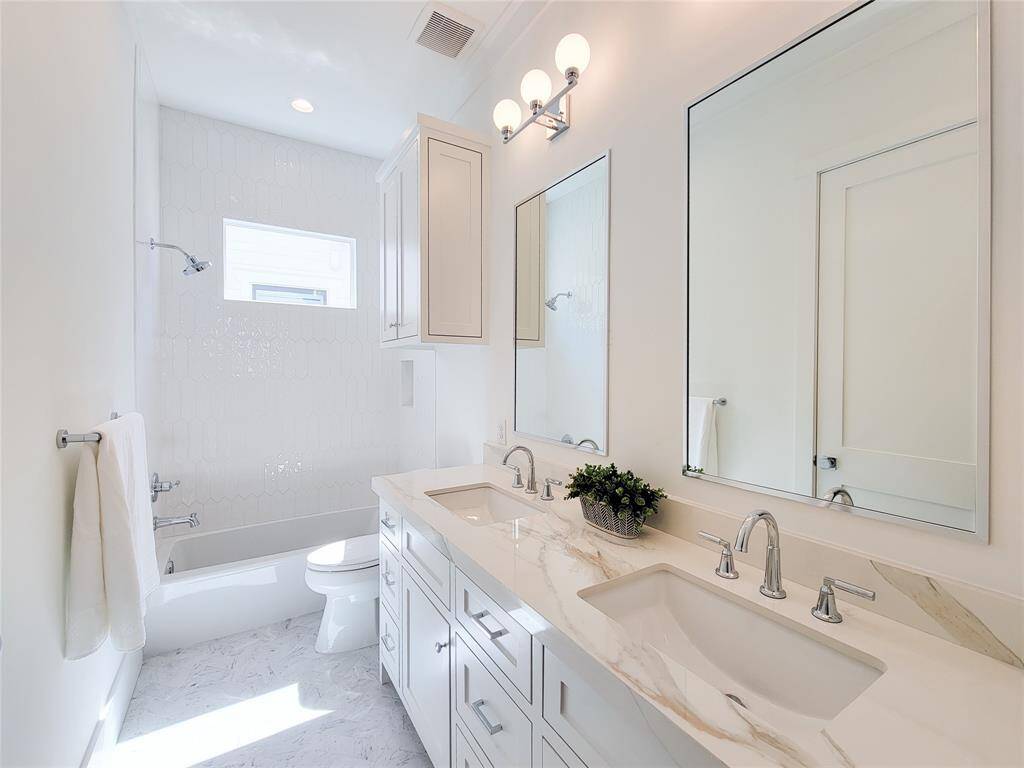 Bath room in the first secondary bedroom offers double sinks and quartzite countertops.