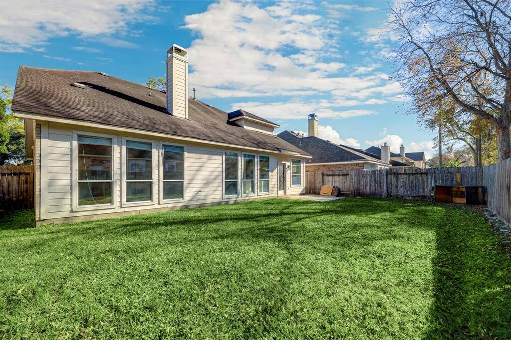 Spacious backyard with lush grass, fenced for privacy. Features large windows on the house for ample natural light. Ideal for outdoor activities and relaxation.