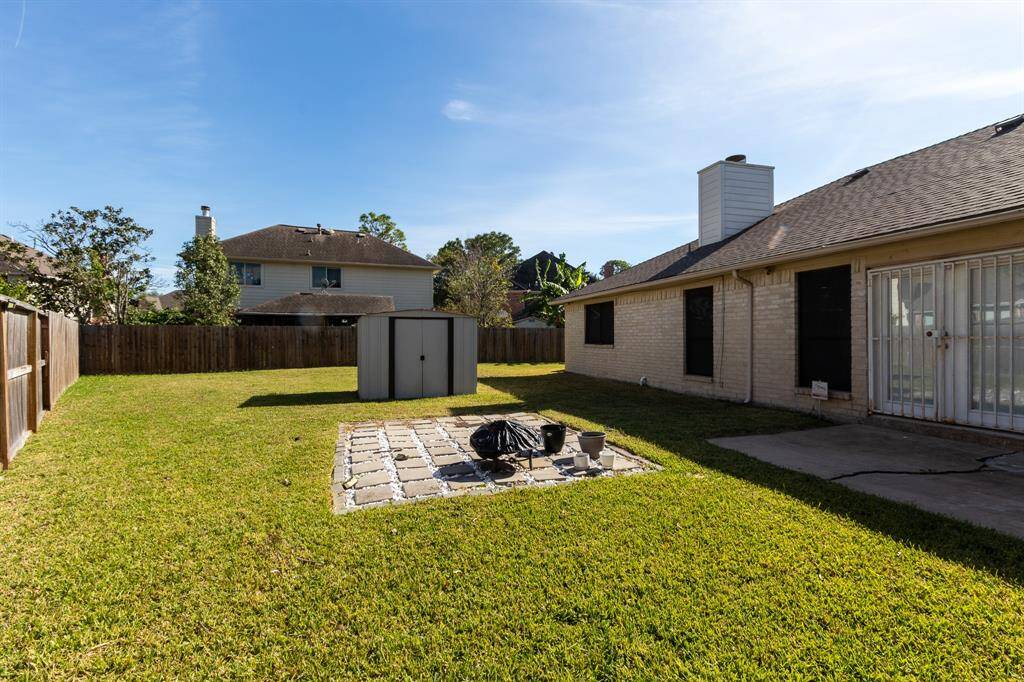 Look at all this space!  This park-like backyard features a well maintained lawn, a central patio area plus a separate patio area perfect for lounging around a fire pit and a storage building, all enclosed by a wooden fence.