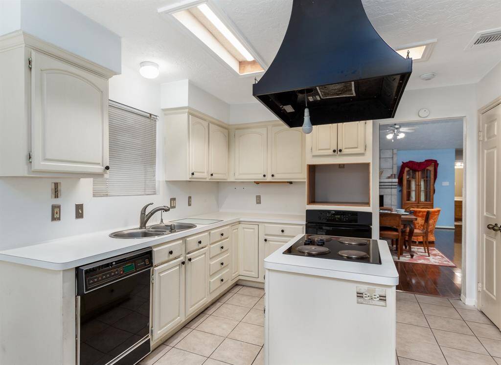 The kitchen offers tile floors, double door panty and window above the triple basin sink.