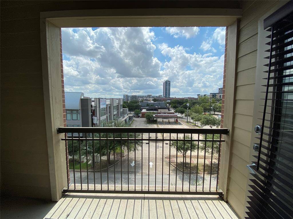 larger balcony with black railing, outdoor light, and a view of downtown