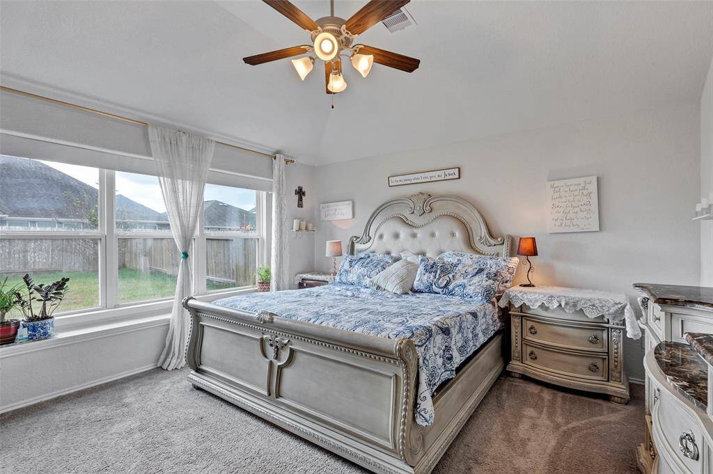 Relax in the spacious main bedroom, featuring a cozy carpeted floor and a wide glass window that offers a serene view of the backyard.