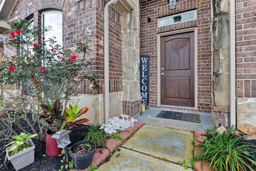 A charming entrance with a rich dark brown wooden door, complemented by a beautiful brick and cement exterior.