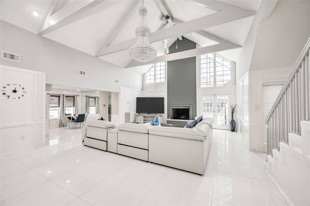 This beautifully designed living room, where wall-to-ceiling windows, flood the space with natural light and offer stunning views of the outdoors. The room is anchored by a modern fireplace, serving as a warm and stylish focal point. Positioned conveniently for entertainment, a sleek TV complements the inviting atmosphere, making this space perfect for relaxing or hosting gatherings.