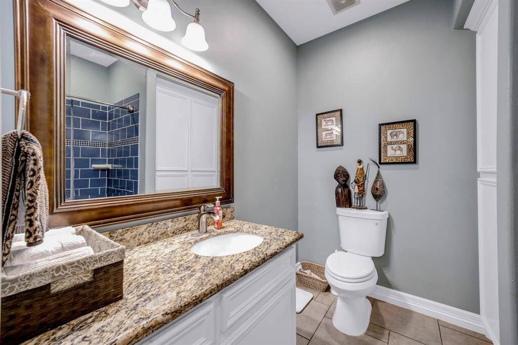 Secondary bathroom with granite counter top sink, framed mirror and tile flooring