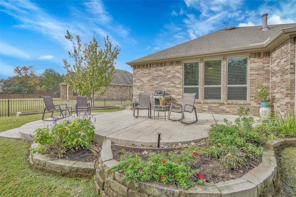 Custom patio expansion with elevated landscape beds and healthy green grass offer a sophisticated look and feel to this oversized backyard space.