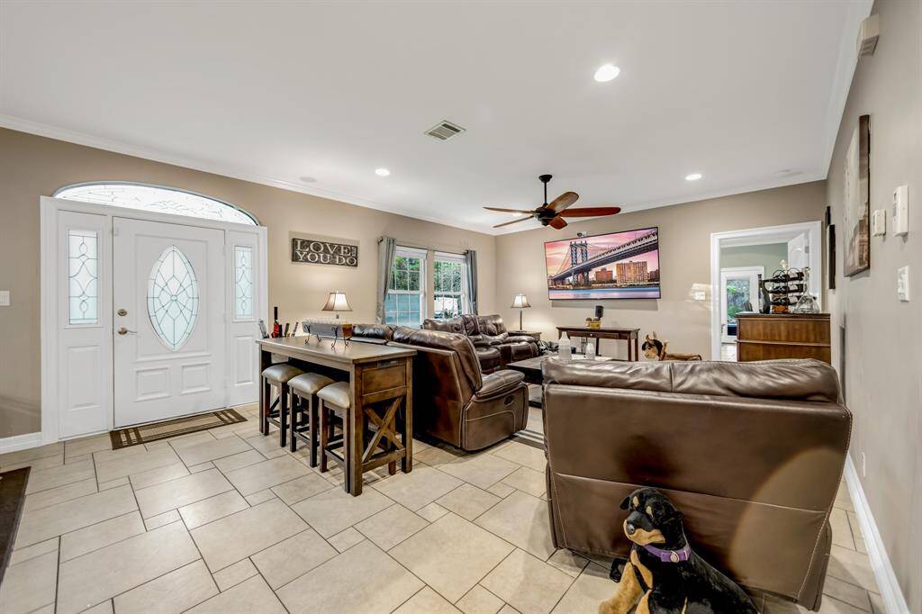 The spacious family room features canister lights, crown molding,ceiling fan and patterned tile flooring