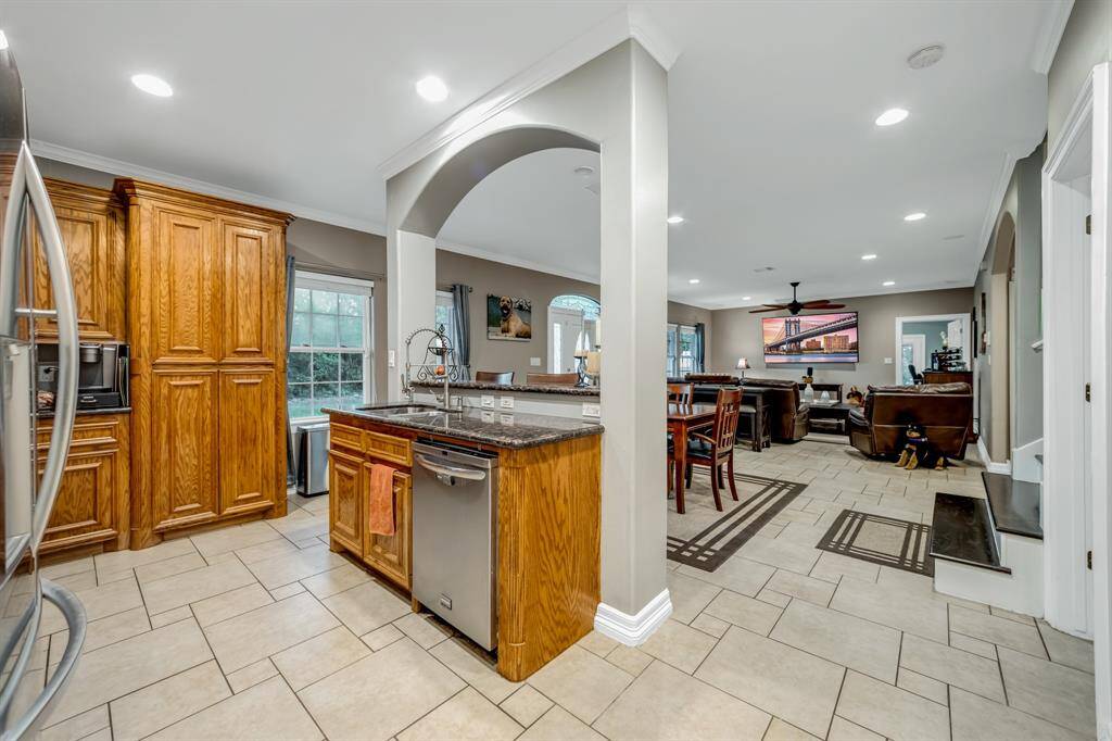 Lovely arched island with sink, dishwasher, crown molding and breakfast bar divides the kitchen to dining