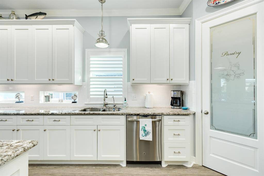 Transom window features under the upper cabinets add a nice touch to this light & bright kitchen. Spacious pantry storage close by for convenience.