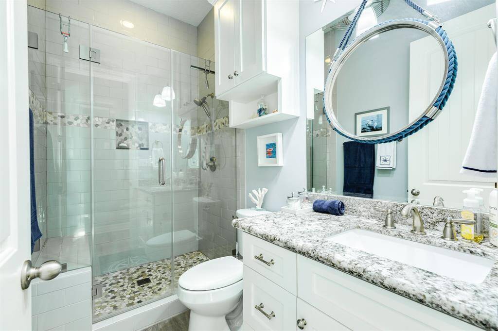 Hall bathroom, nicely finished with a granite topped vanity, custom cabinets and frameless glass walk-in shower.