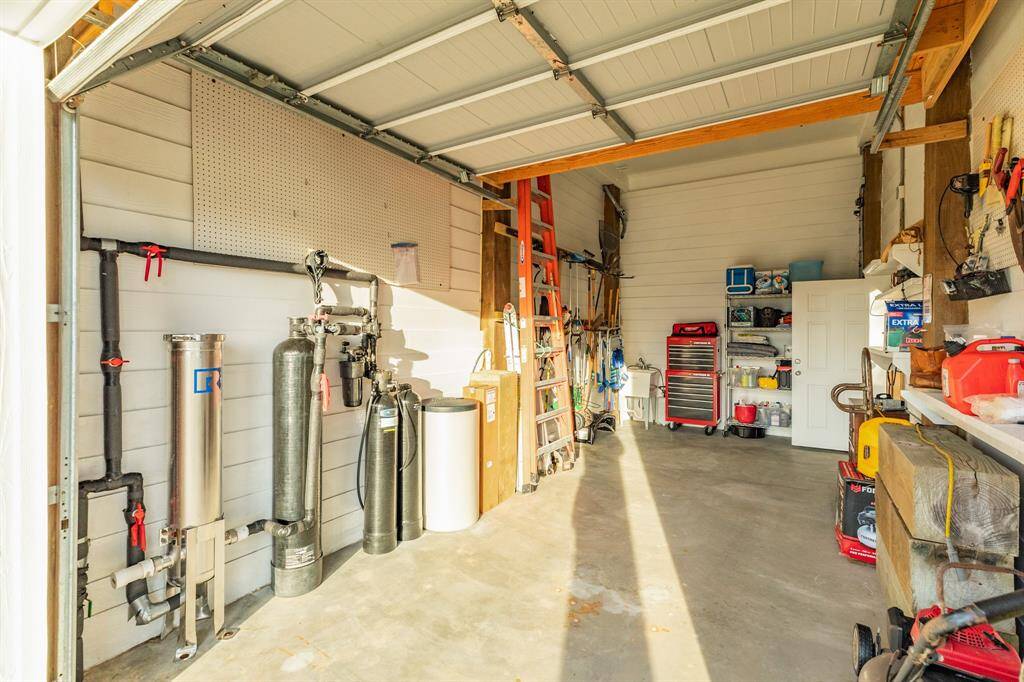 Spacious one car garage with overhead shelving storage. In view on the wall is the water purification system for the home.