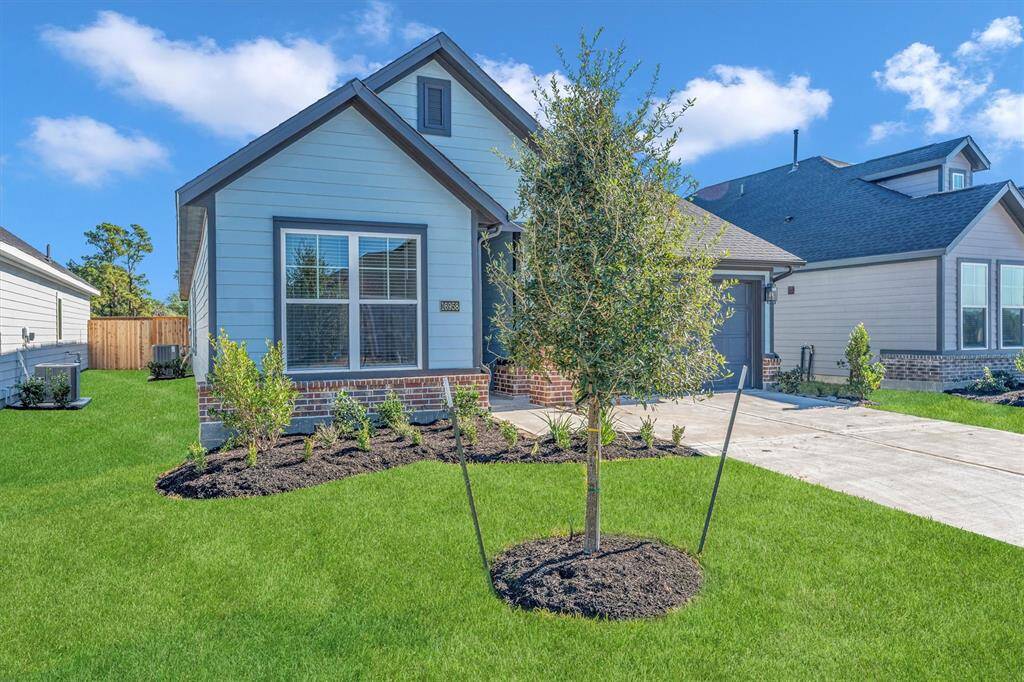 Charming single-story home with modern siding and brick accents. It features a well-maintained lawn, young trees, and attractive landscaping. The driveway leads to a welcoming entrance, ideal for a cozy residence.