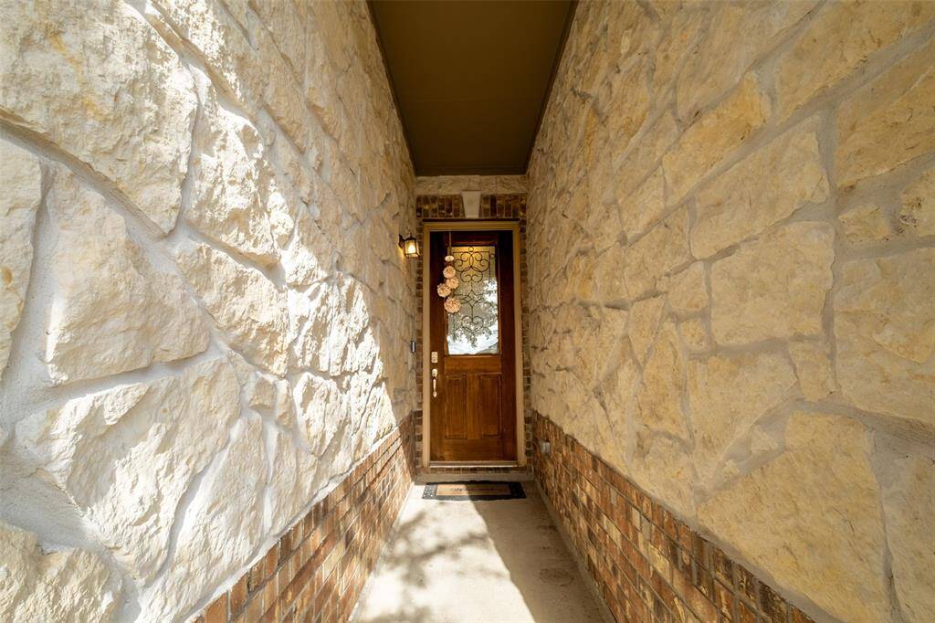 Welcoming stone entryway leading to a wooden front door with decorative glass, offering a charming and rustic first impression.