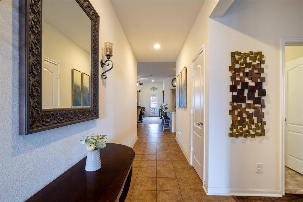 Hallway with tiled flooring. The space is well-lit and leads into an open living area, creating a warm and inviting entryway.