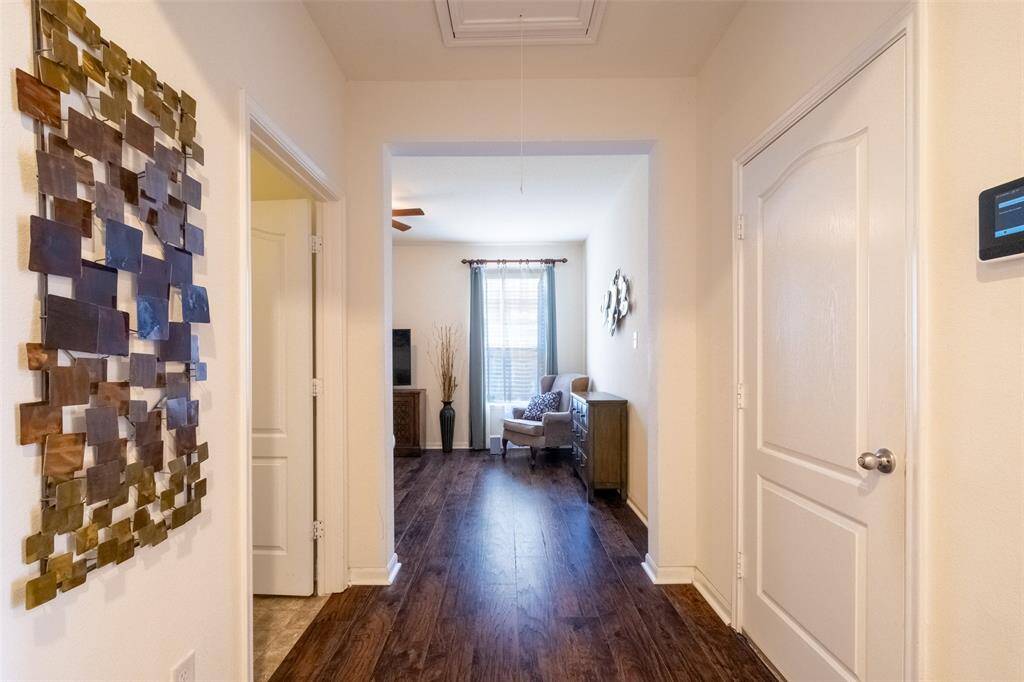 A bright hallway with hardwood floors leads to office/flex space, featuring a large window, neutral walls.
