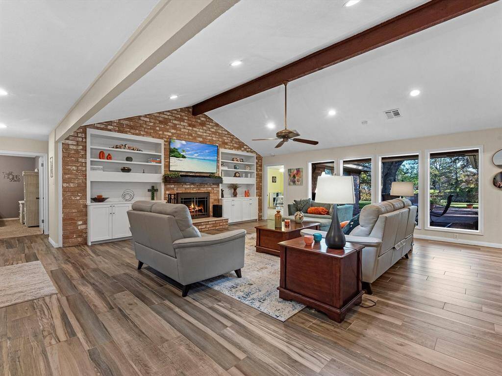 Living Area (1 of 2) with vaulted beamed ceiling, fireplace (1 of 2), custom built-ins, and floor to ceiling windows for a perfect view of the Lake