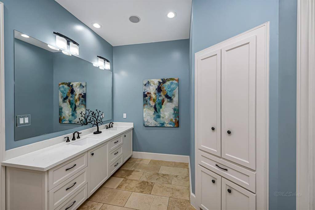 Primary bath offer dual sinks, custom cabinets, and built in hamper/storage space
