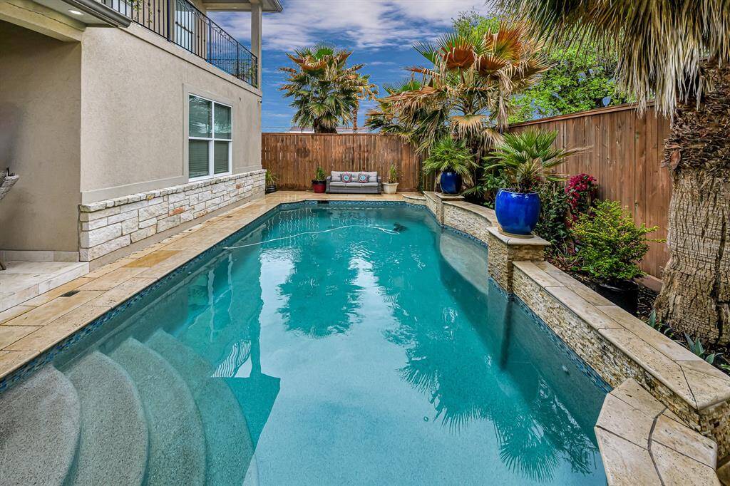 The centerpiece of this yard is a stunning, resort-style pool, its crystal-clear water glistening under the sun