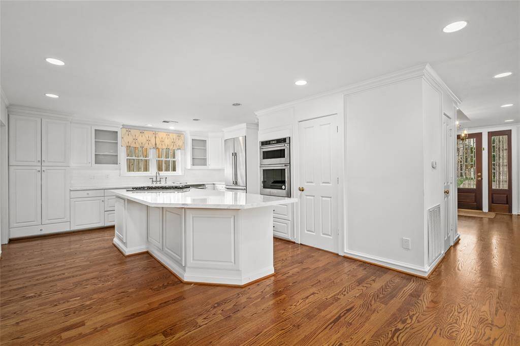 Another view of the kitchen. Cased opening to the dining room to the right of the refrigerator. New KitchenAid convection oven and microwave. Walk in pantry. Seating for three at the island.  Virtually Staged.