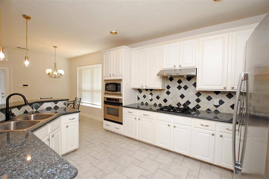 Kitchen with granite countertops and stainless steel appliances open to the living