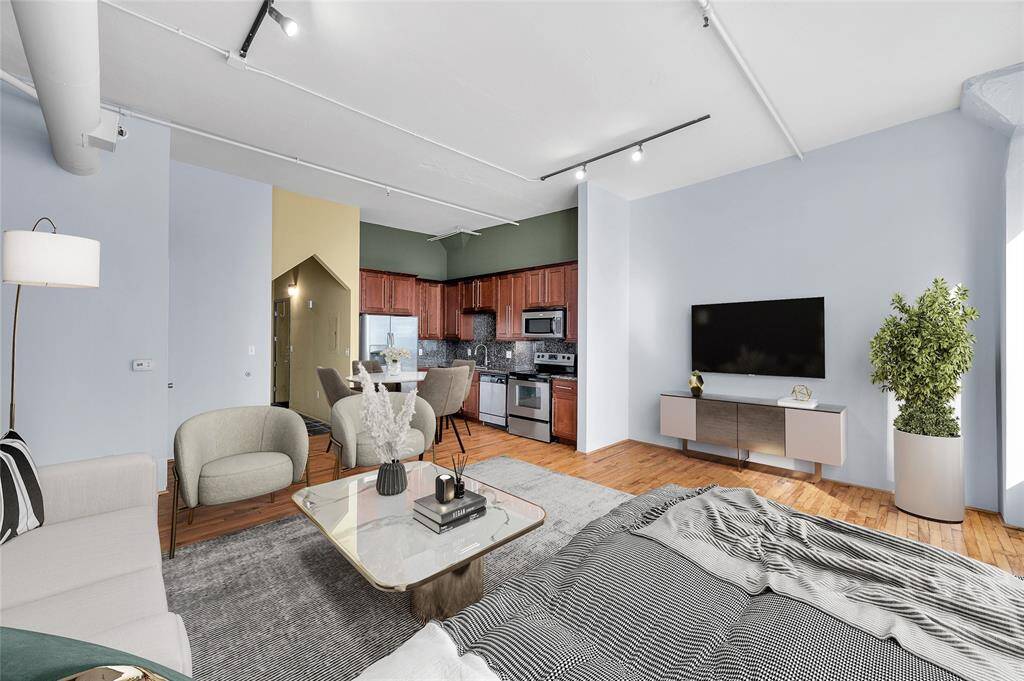 This view shows ability to create different functioning areas for sleeping, living and dining in this cool studio loft! Reclaimed wood floors in this space. Hallway leads to Entry, Bath & Closet. PHOTO VIRTUALLY STAGED.