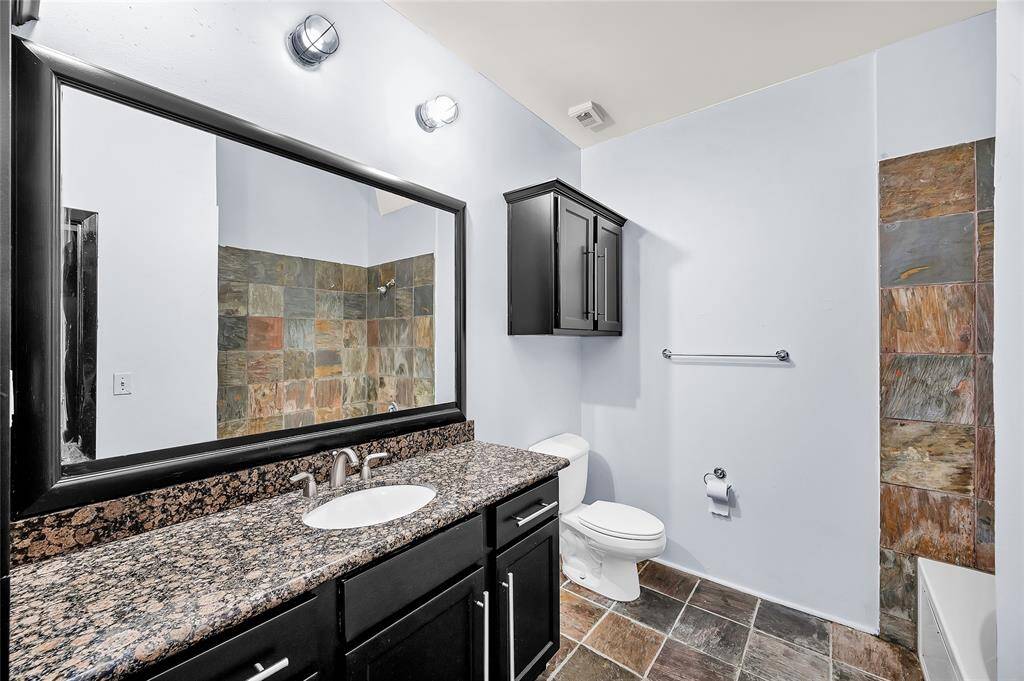 Large Bathroom features recently painted vanity with door and drawer storage, cabinets over toilet and large soaking tub with shower combo.  Slate tub surround and floors.