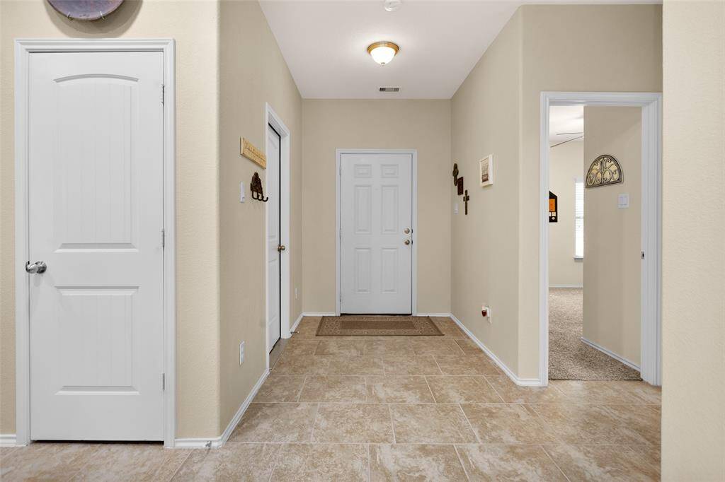 This view is looking back to the front door with garage access to the left and secondary bedroom on the right.
