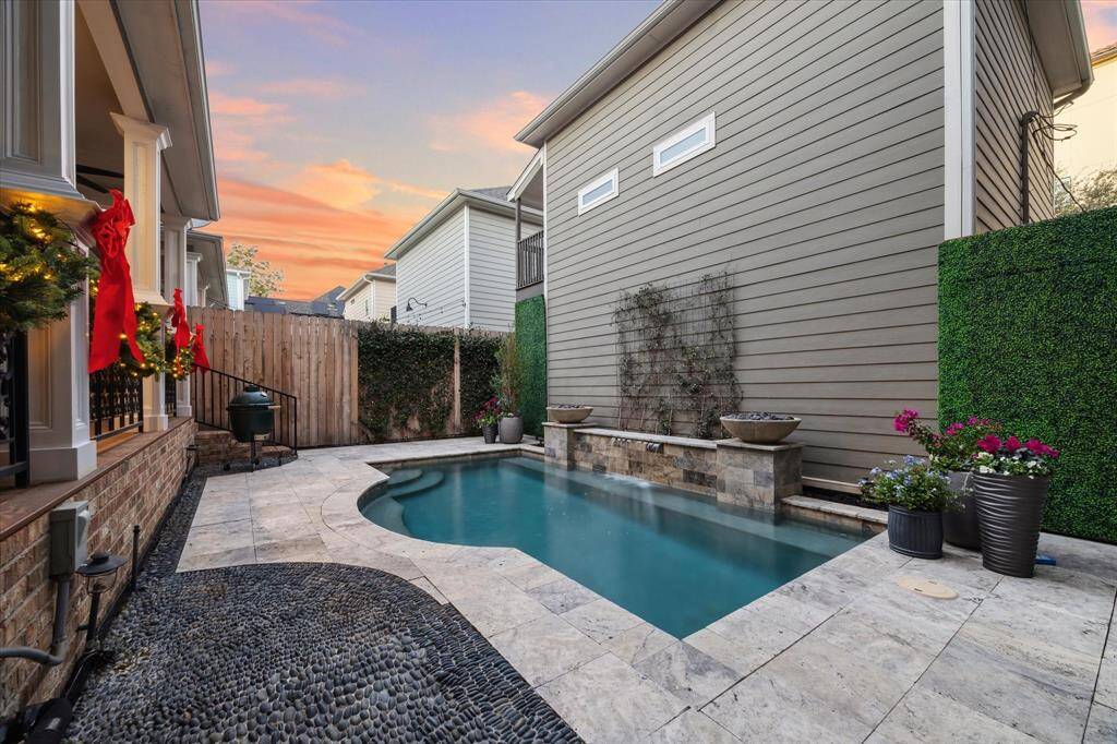 The cozy backyard with a small, modern pool surrounded by a stone patio. The area is accentuated with planters and a privacy fence, offering a serene outdoor retreat.
